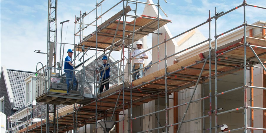 Bouwvakkers op steiger bij nieuwbouwwoningen