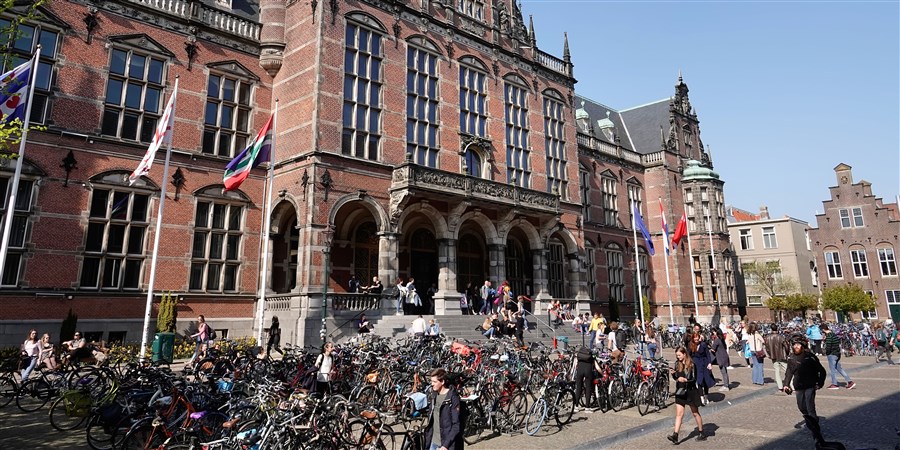 Studenten zitten op de trap voor het Academiegebouw in Groningen