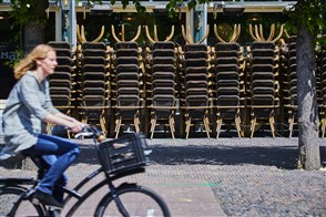 Een vrouw fietst langs opgestapelde terrasstoellen op de grotemarkt in Haarlem