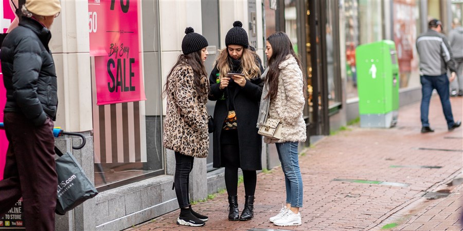 een groepje meisjes dat staat te wachten voor een winkel