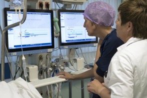 Verpleegkundigen van de verkoeverkamer aan een beeldscherm bezig met de administratie en invoeren van patientengegevens.