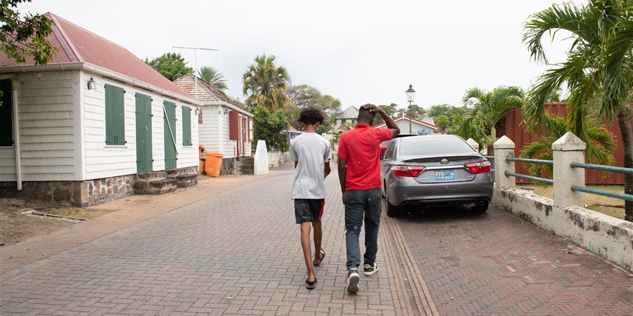Daily life on St Eustatius. Street with house, people and car.