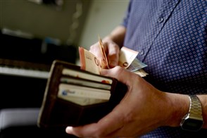 Persoon pakt papiergeld uit zijn portemonnaie