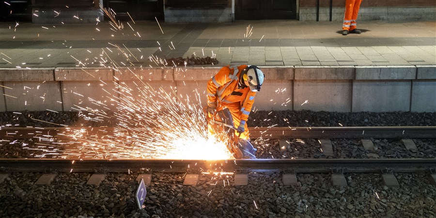 Man pleegt onderhoud aan de rails bij Hollands Spoor