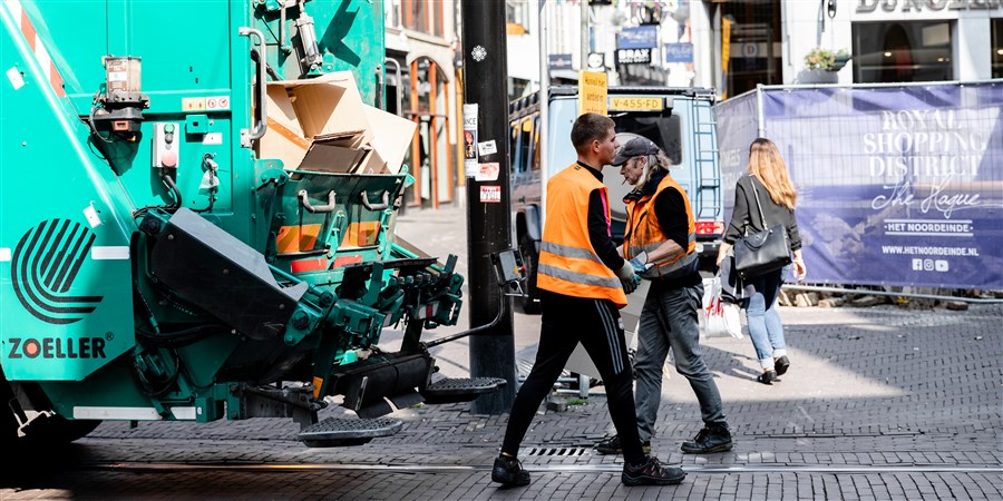 twee vuilnismannen die het karton in de winkelstraten van Den Haag ophalen