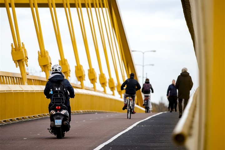 Snorfietser met helm rijdt op brug