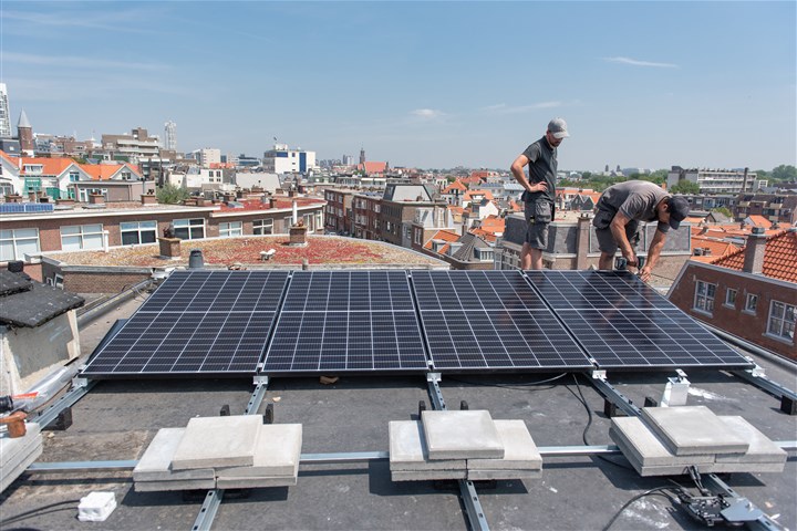 Mensen installeren zonnepanelen op het dak van een woonhuis op Scheveningen