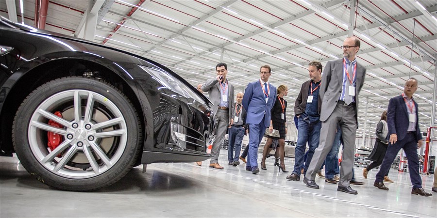 Zakenmensen bekijken elektrische auto's in de nieuwe Tesla fabriek in Tilburg