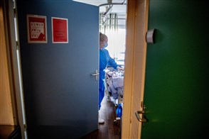 Verpleegkundige die aan het werk is in een kamer vanuit smalle deuropening gezien