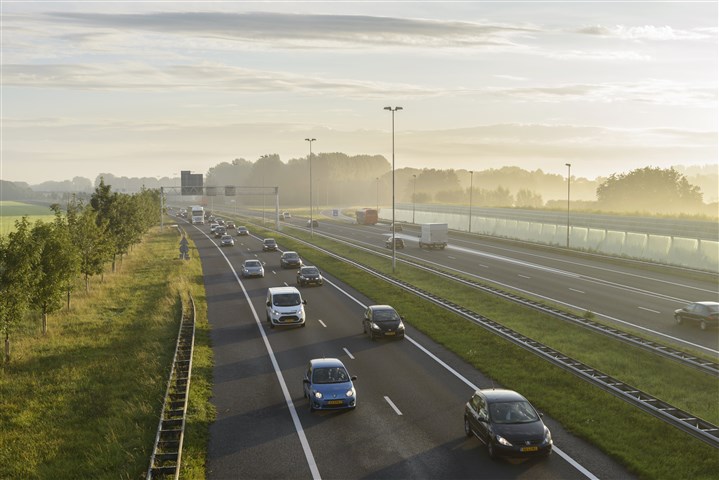Verkeer opp de snelweg tijdens een heiige ochtend. De zon komt links op door de ochtendmist