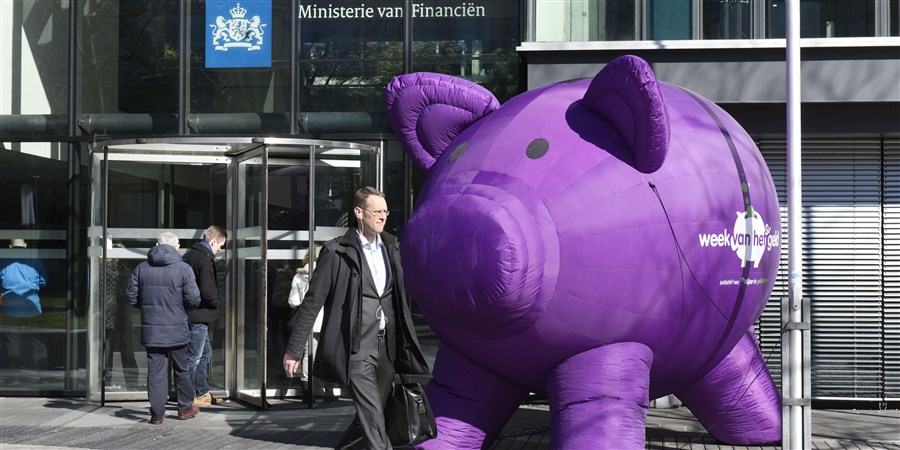 Een groot paars spaarvarken staat voor de ingang van het ministerie van financien