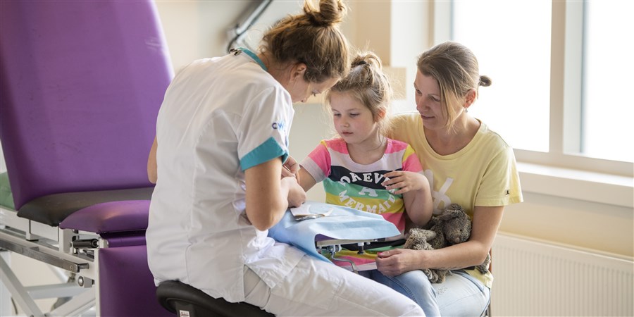 Verpleegkundige helpt kind in de gipskamer van het ziekenhuis