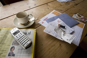 tafel met een kop koffie, telefoon en allerlei papieren