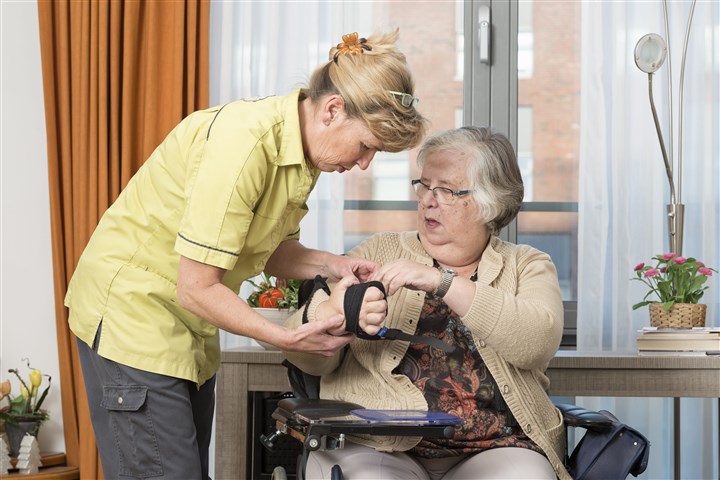 Verpleegkundige helpt oudere dame met het aanbrengen van een brace