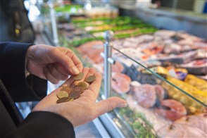 Oudere telt geld bij kassa van slager