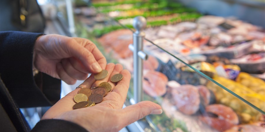 Oudere telt geld bij kassa van slager