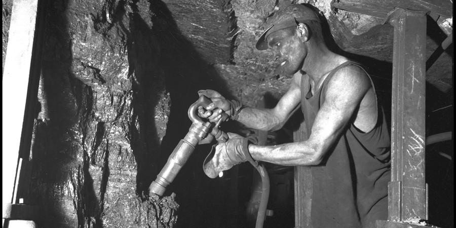 Mijnwerker met afbouwhamer aan het werk op ongeveer 600 meter diepte in de staatsmijn Maurits. Geleen, 1947. Mijnwerker met afbouwhamer aan het werk op ongeveer 600 meter diepte in de staatsmijn Maurits. Geleen, 1947.