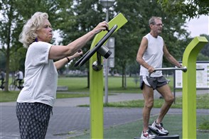 Een vrouw sport in openbare fitness ruimte. Op de achtergrond is haar echtgenoot ook aan het sporten.