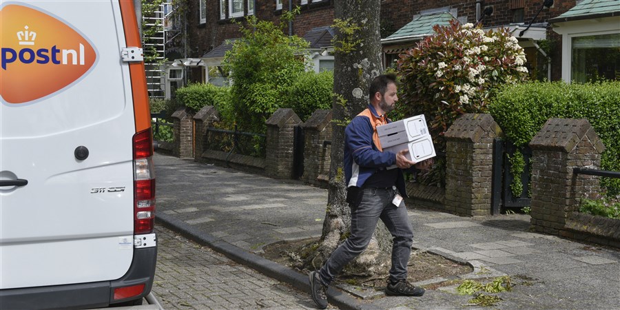 Postbezorger van PostNL levert pakketjes af bij woonhuis