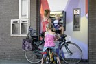 Een vrouw met twee kleine kinderen neemt geld op bij een pinautomaat