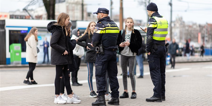 Afbeelding: twee politiemannen die bij groep meisjes staan