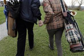 Ouder echtpaar hand in hand op de golfbaan