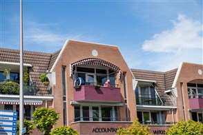 Mensen op balkon van appartement in Twente boven accountantskantoor
