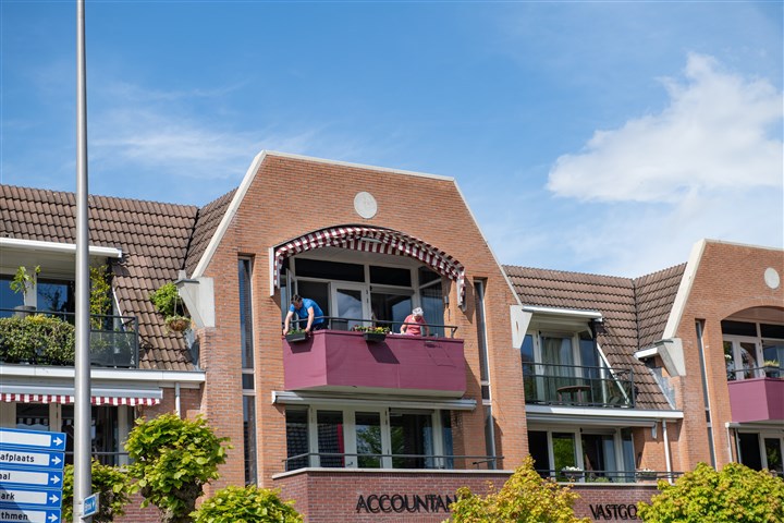 Mensen op balkon van appartement in Twente boven accountantskantoor