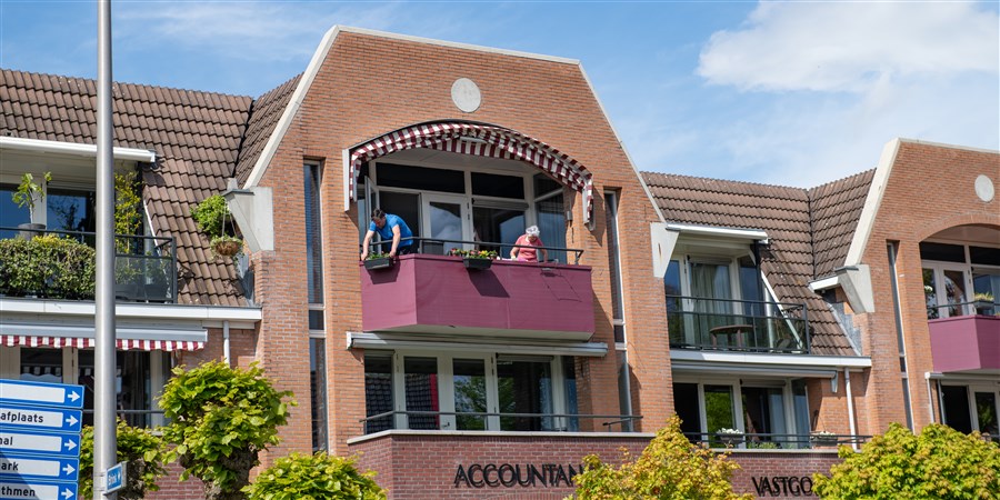 Mensen op balkon van appartement in Twente boven accountantskantoor