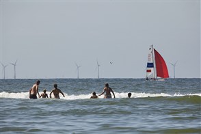 Mensen in de zee met tegen de achtergrond windmolenpark
