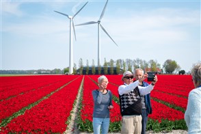 Toeristen maken een selfie bij de bollenvelden met op de achtergrond twee windmolens