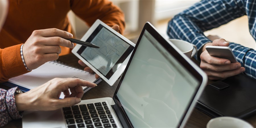 collega's die op laptop, ipad en telefoon aan het werk zijn.