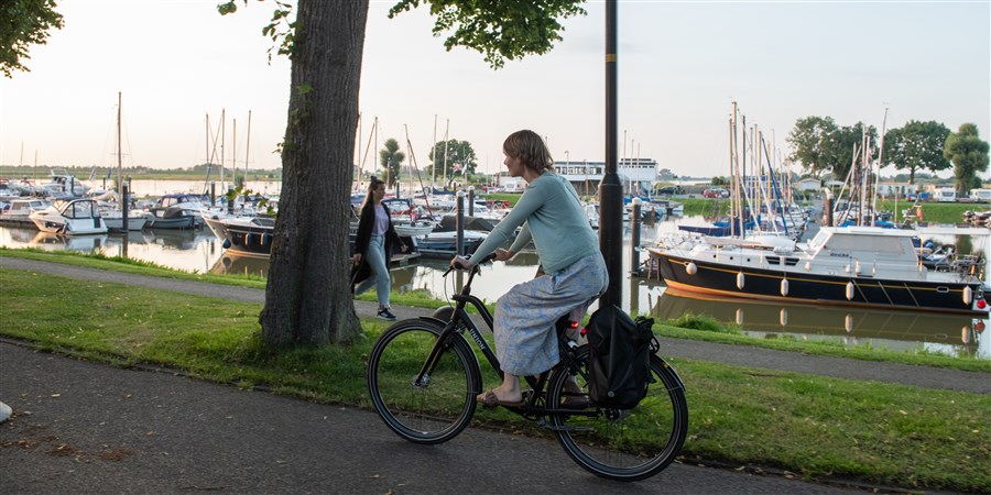 Jonge vrouw op de fiets rijd op fietspad in Culemborg