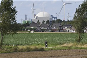 Fietser rijdt door  landschap met in de achtergrond de kerncentrale Borssele