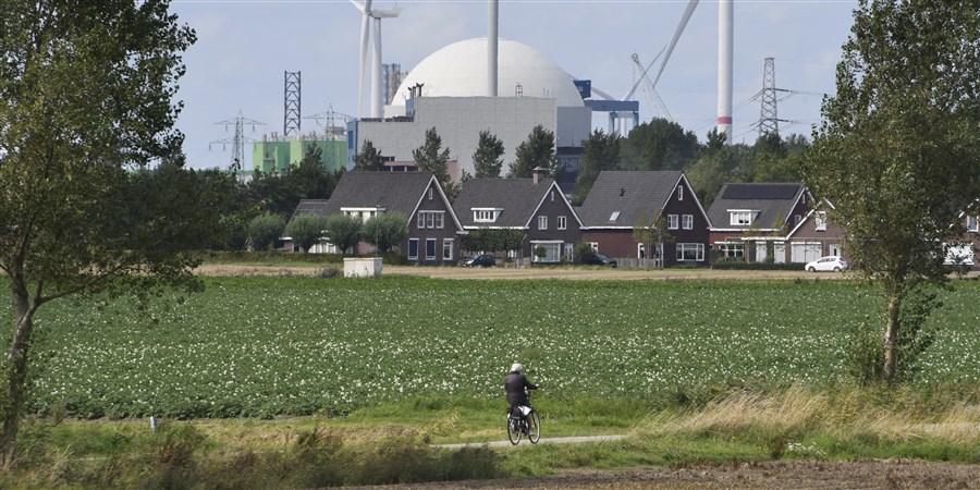 Fietser rijdt door landschap met in de achtergrond de kerncentrale Borssele