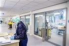 Zorgmedewerker met beschermende kleding vult formulier in op de intensive care afdeling van het ziekenhuis waar coronapatiënten worden geholpen aan hun klachten.