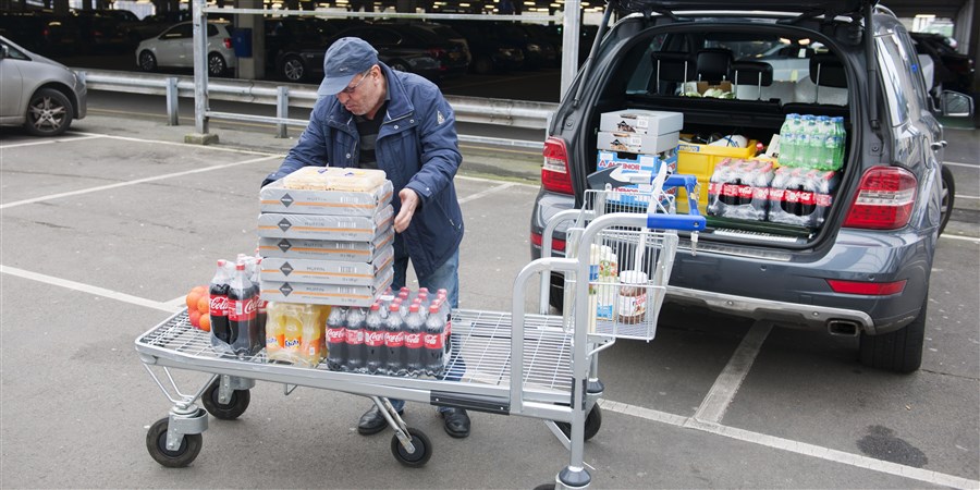 Man pakt boodschappen van groothandel-boodschappenwagen over in zijn auto