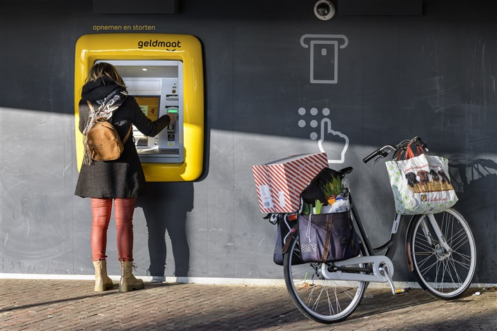 Vrouw met boodschappen bij geldautomaat
