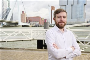 Patrick, statistisch onderzoeker op de Willemskade in Rotterdam, met Erasmusbrug op de achtergrond