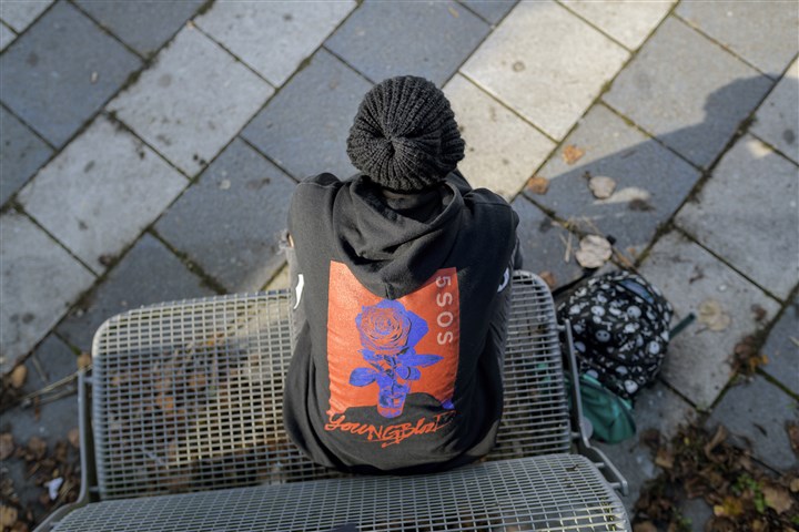 Jonge meid in zwarte kleding hangt alleen op bankje in een park, depressief en in gedachten