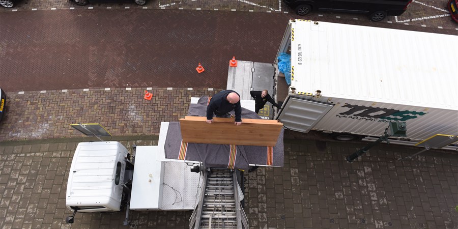 Verhuizers verhuizen de inboedel uit een appartement met verhuislift in verhuiswagen