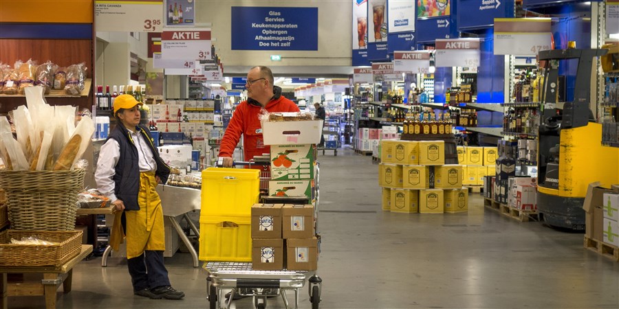 Man met volgeladen boodschappenwagen in groothandel