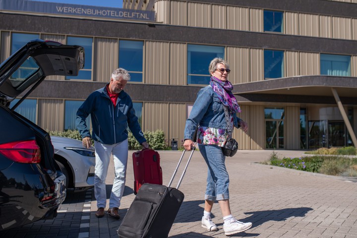 Ouder stel met koffers bij hotel