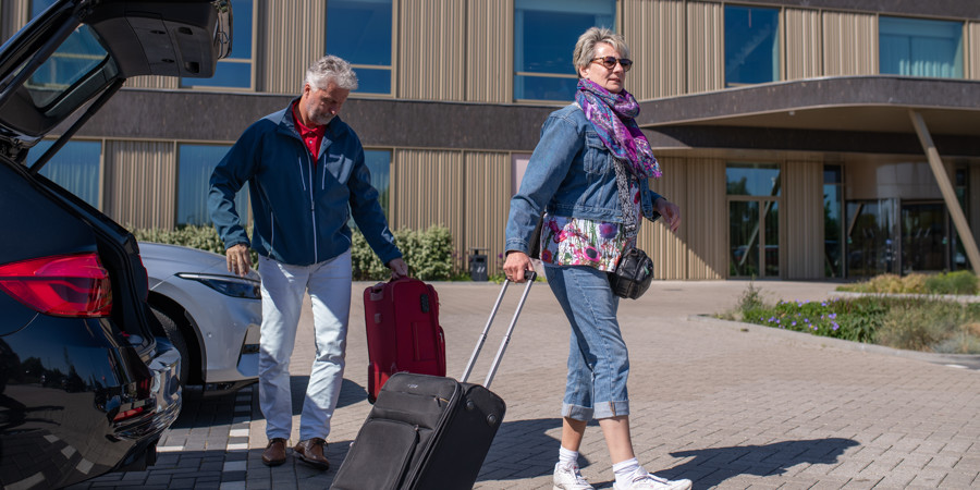 Ouder stel met koffers bij hotel