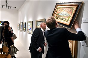 Twee mannen bekijken een schilderij op de Tefaf kunstbeurs