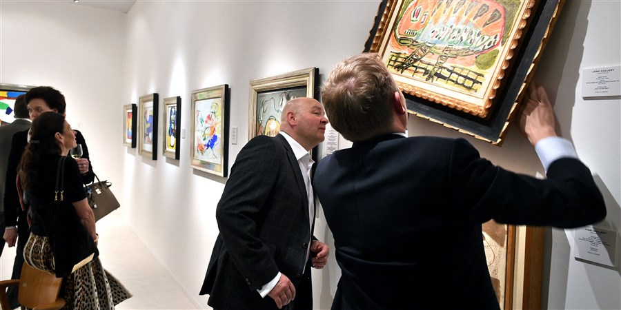 Twee mannen bekijken een schilderij op de Tefaf kunstbeurs