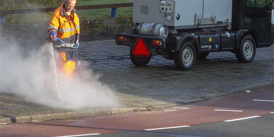 Een medewerker van de gemeente Amstelveen is bezig met het verwijderen van onkruid middels een stoomspuit, onkruidbestrijding met heet water.
