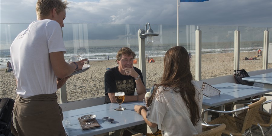 Man bedient twee klanten in een strandpaviljoen