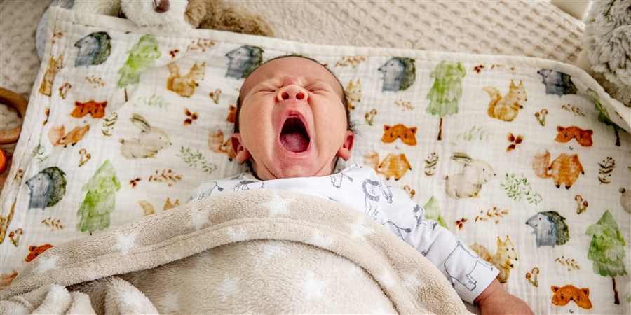 Een baby ligt in zijn bedje te slapen