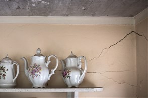 Antieke theekannen op plak aan muur met scheur er in